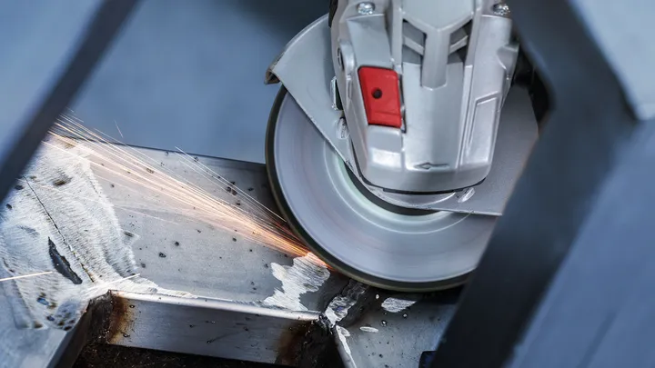 Rebarbadora a cortar uma viga de metal, produzindo faíscas.