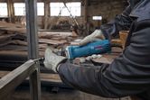 Uma pessoa que utilize equipamento de segurança esmerilha uma estrutura metálica com uma esmerilhadora reta.