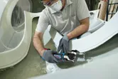 Una persona que usa equipo de seguridad corta fibra de vidrio con una herramienta multiusos inalámbrica.