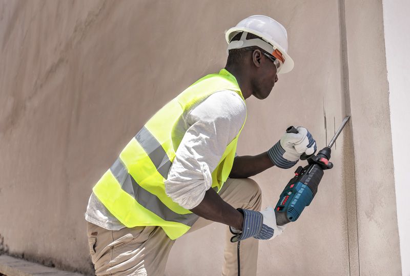 Una persona que usa equipo de seguridad utiliza una herramienta eléctrica para cortar una pared de hormigón.