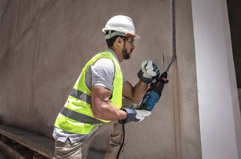 Una persona que usa equipo de seguridad utiliza una sierra alternativa para cortar una pared de hormigón.