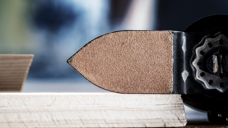 Lijadora de detalles alisando la superficie de un borde de madera.