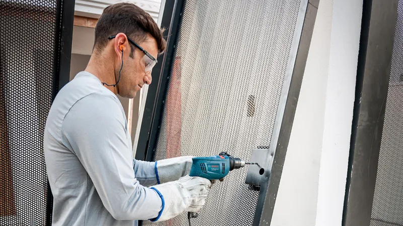 Una persona que usa equipo de seguridad perfora un marco de metal utilizando un taladro de impacto.