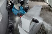 Una persona que usa equipo de seguridad utiliza un cortador de bloques AAC para cortar un bloque de concreto.