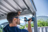 Una persona que usa equipo de seguridad utiliza una llave de impacto inalámbrica sobre una estructura metálica.