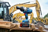 Llave de impacto inalámbrica apoyada sobre orugas de maquinaria pesada en un sitio de construcción.