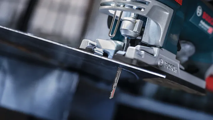 Una sierra de calar corta una lámina de metal en un taller.