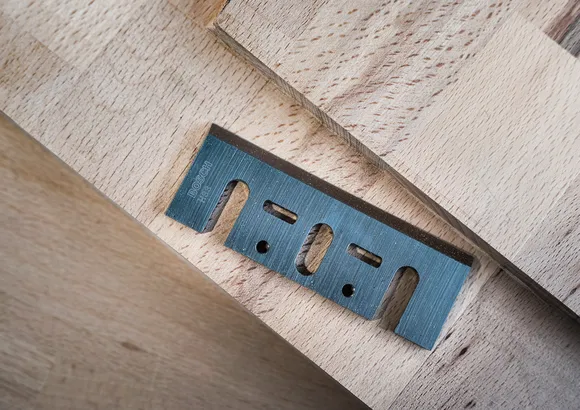 Hoja multiusos de metal colocada sobre tablas de madera apiladas.