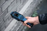 Una persona utiliza un medidor de humedad de materiales para comprobar la humedad en una pared de ladrillos.