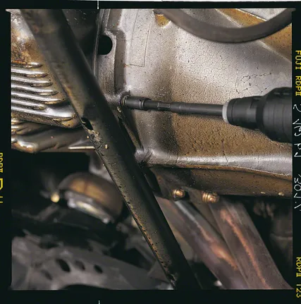 Ein Akkuschrauber zieht eine Schraube an einem Motorgehäuse aus Metall fest.