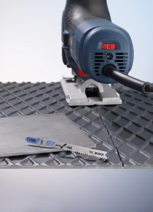 Stichsägenschneiden eines Metallblechs auf einer strukturierten Oberfläche.