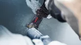 Eine Person benutzt die Klinge eines Multifunktionswerkzeugs, um ein Kunststoffrohr durchzuschneiden.