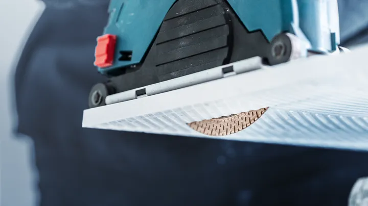 Eine Kreissäge schneidet eine Nut in eine weiße Keramikfliese.