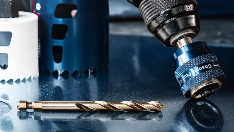 Eine Nahaufnahme eines Bohrfutters und eines Bohrers auf einer reflektierenden Metalloberfläche.