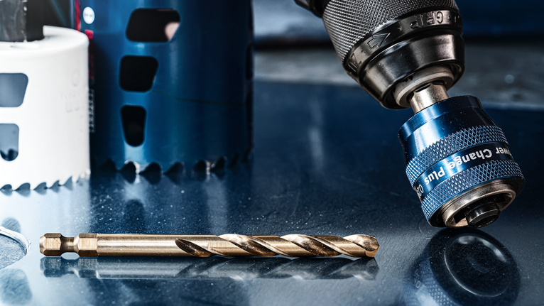 Eine Nahaufnahme eines Bohrfutters und eines Bohrers auf einer reflektierenden Metalloberfläche.