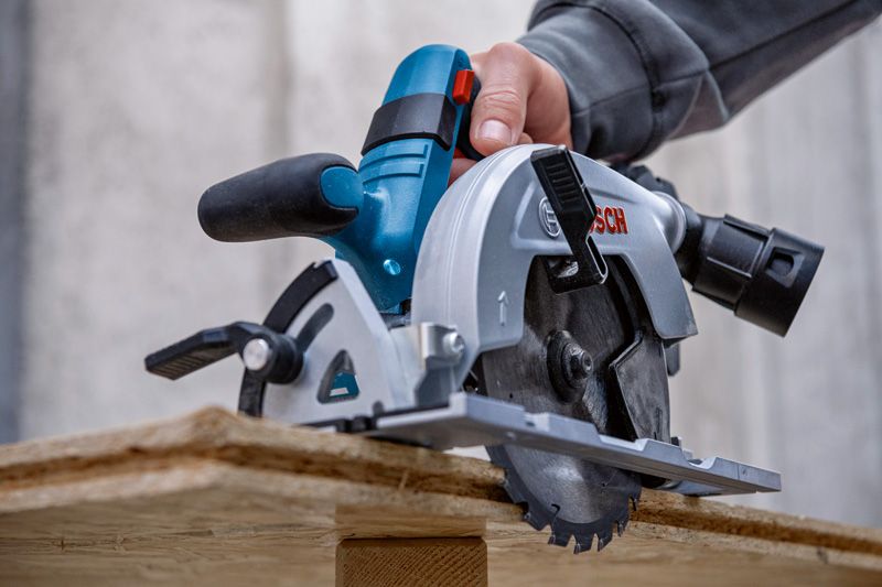 Eine Person schneidet auf einer Baustelle Holz mit einer Kreissäge.