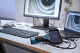 Inspektionskamera, die an einen Laptop auf einem Bürotisch angeschlossen ist, mit Rohrbildern auf Bildschirmen.