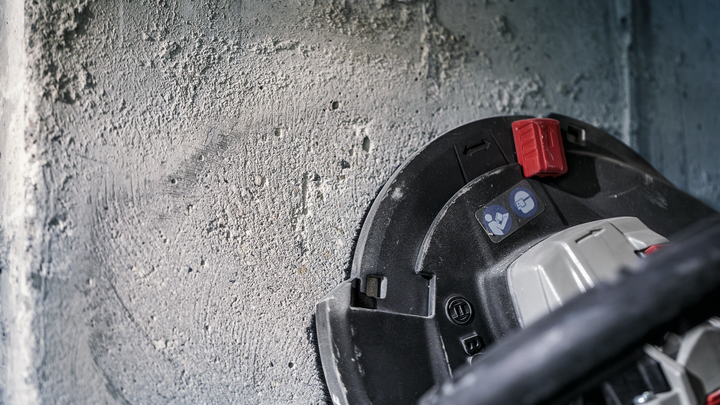 Ein Werkzeug schleift eine raue Betonwand.