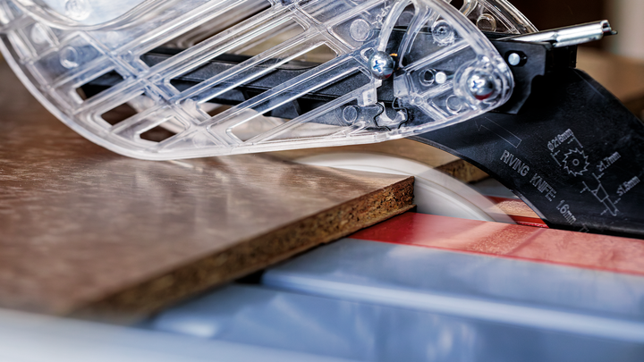 Eine Kreissäge schneidet in einer Werkstatt durch ein Holzbrett.