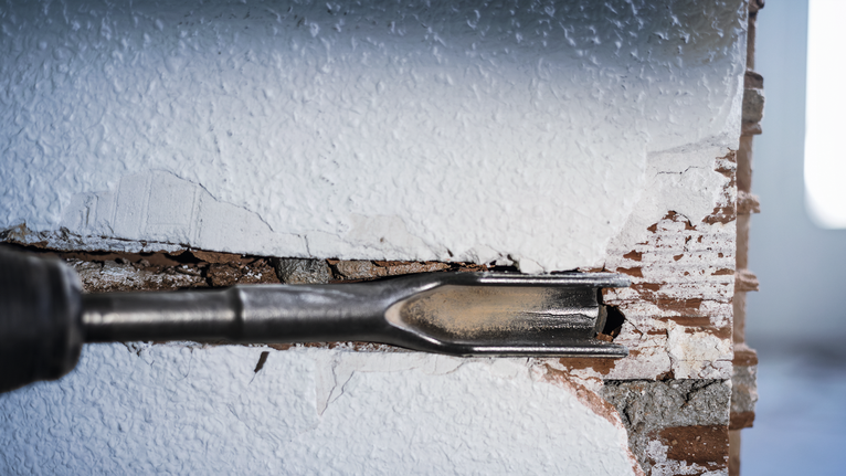 Meißel zum Brechen von Putz und Ziegeln aus einer Wand.