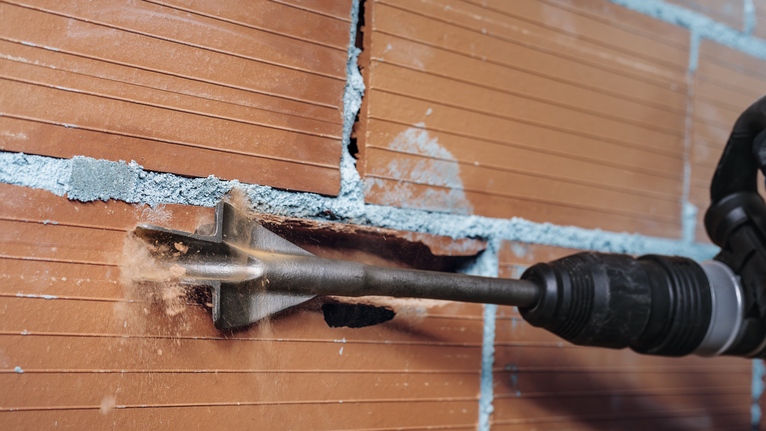 Bohrhammermeißel zum Entfernen von Ziegelmaterial aus einer Wand.