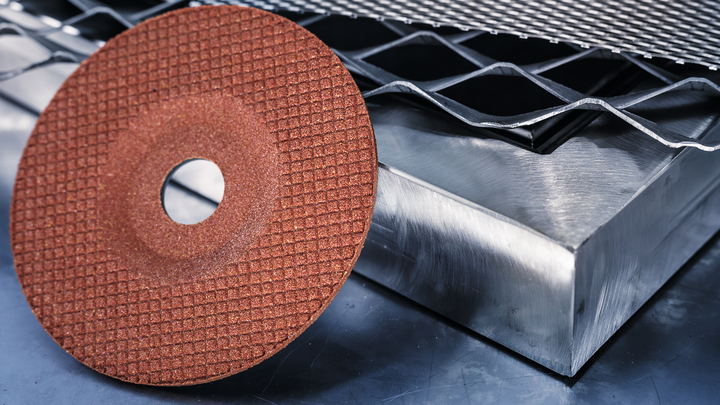Eine Schleifscheibe, die auf einer Metalloberfläche neben einem Metallgitter platziert ist.