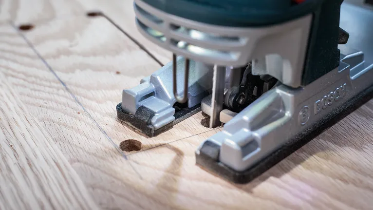 Mit einer Stichsäge wird eine rechteckige Form aus einem Holzbrett geschnitten.