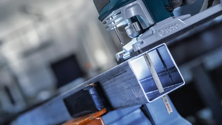 Ein Elektrowerkzeug schneidet in einer Werkstatt durch einen Metallträger.