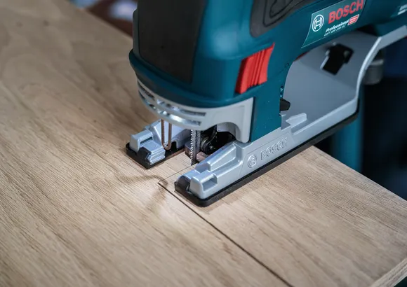 Stichsäge schneidet eine gerade Linie durch ein Holzbrett.