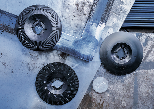 Drei Schleif- und Trennscheiben aus Metall, angeordnet auf einer zerkratzten Metalloberfläche.