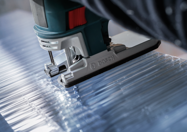 Durchsichtige Acrylplatten werden mit einer Stichsäge entlang gerader Linien geschnitten.