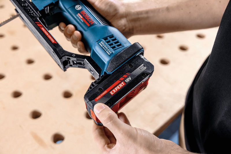 Eine Person setzt einen Akkupack in eine Akku-Stichsäge auf einer Werkbank ein.