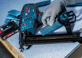 Eine Person, die Schutzausrüstung trägt, lädt Klammern in einen kabellosen Mittelhefter.