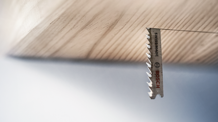 Stichsägeblatt schneidet von unten durch ein Holzbrett.