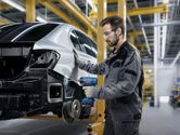 Eine Person, die Schutzausrüstung trägt, benutzt einen Akku-Schlagschrauber an einem Autorahmen.