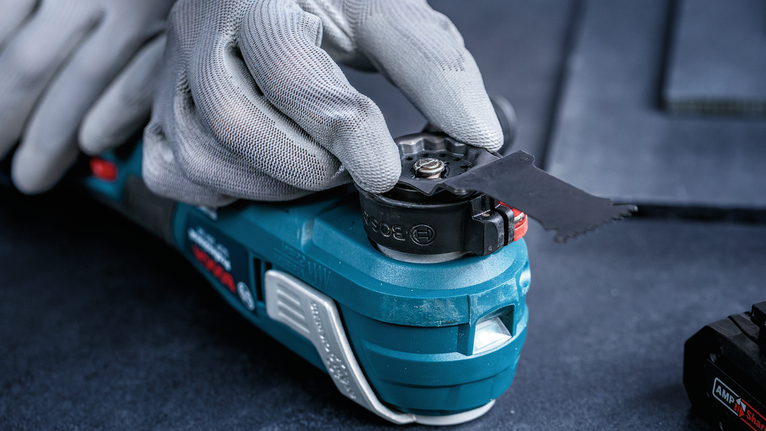 Eine Person, die Schutzausrüstung trägt, befestigt ein Sägeblatt an einem Elektrowerkzeug.