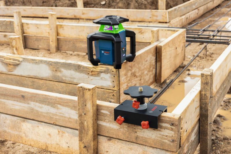 Laser-Nivelliergerät mit Halterung und Montagevorrichtung an einer Holzschalung auf einer Baustelle.