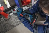 Eine Person, die Schutzausrüstung trägt, schneidet ein Kunststoffrohr mit einer kabellosen Rohrschere durch.