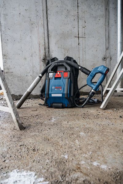 Ein kabelloser Rucksackstaubsauger steht auf dem Boden einer Baustelle.