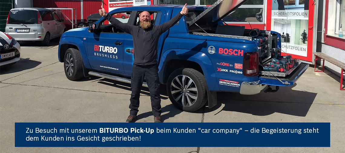 Ein Mann mit Bart zeigt Daumen hoch neben einem blauen Bosch BITURBO Pick-Up.