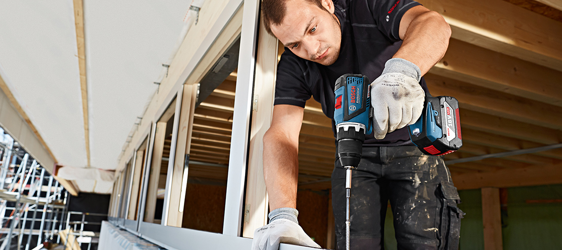 Ein Handwerker nutzt einen blauen Bosch Professional Akkuschrauber in einem Bauumfeld.
