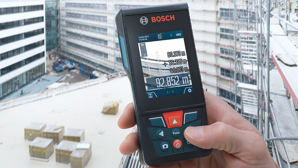 Ein Bosch Professional Entfernungsmesser wird in einer Baustellenumgebung gehalten.