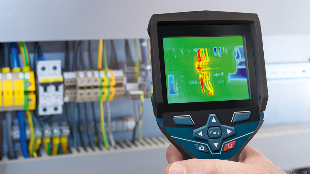 Eine Hand hält ein Bosch Professional Thermokamera-Display, darunter elektrische Komponenten.