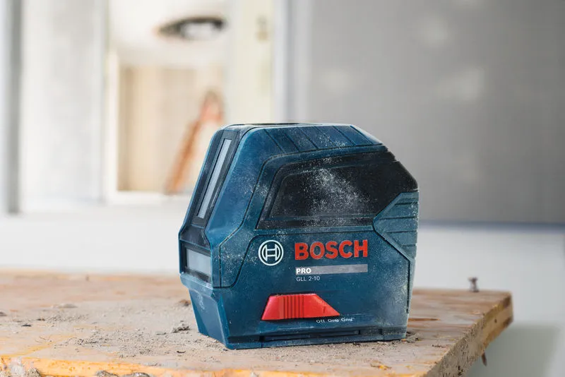 Outil de nivellement laser sur un établi poussiéreux dans un environnement de construction.
