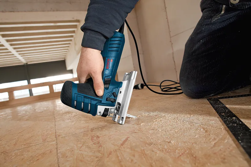 Personne utilisant une scie sauteuse pour couper un plancher en contreplaqué.
