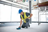 Une personne portant un équipement de sécurité scanne le sol d'un chantier de construction avec un scanner mural.