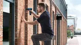 Une personne portant un équipement de sécurité perce un mur de briques à l'extérieur d'un bâtiment.