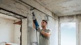 Une personne portant un équipement de sécurité utilise une scie alternative pour couper un tuyau métallique à l’intérieur.
