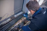 Une personne portant un équipement de sécurité inspecte un drain avec une caméra d'inspection.