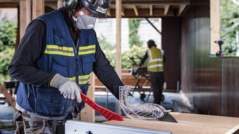 Une personne portant un équipement de sécurité ajuste un protège-lame de scie sur un chantier de construction.